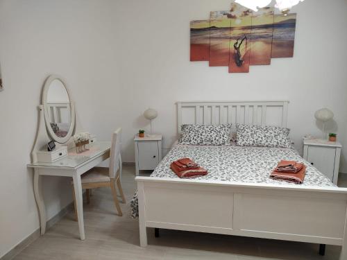 een slaapkamer met een wit bed, een spiegel en een tafel bij Holiday house Chiara in Giardini Naxos