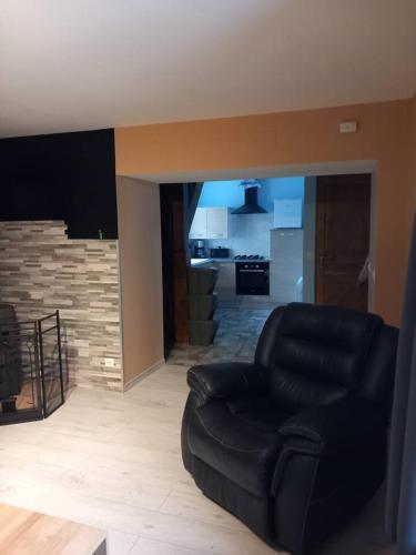 a living room with a black chair and a kitchen at demeure de la vielle tour in Rancourt