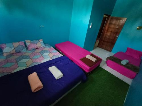 a room with a bed with purple sheets and pink pillows at Backpackers Homestay in Labuan Bajo