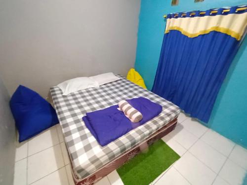 a small bed in a room with a blue curtain at Backpackers Homestay in Labuan Bajo