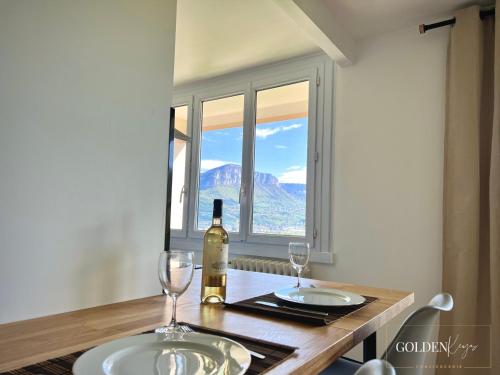 a table with a bottle of wine and two glasses at Le Golden View - Vue Imprenable & Parking Gratuit in Chambéry