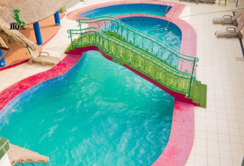 a swimming pool with a bridge in the water at New Green Horse Hotel in Cotonou