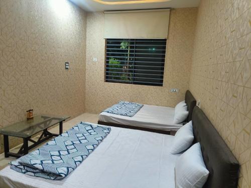 two twin beds in a room with a window at Nataraj Homestays in Ujjain