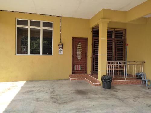 une maison jaune avec une porte et une fenêtre dans l'établissement Homestay Al amin 2, à Kampong Sura Tengah