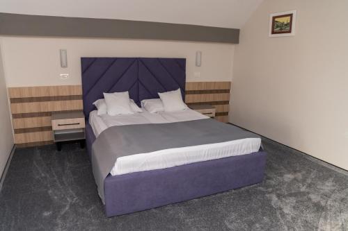 a bedroom with a large bed with a purple headboard at Complex Turistic Monaco in Baile Felix