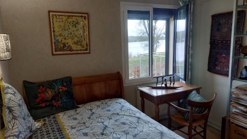 Schlafzimmer mit einem Bett, einem Tisch und einem Fenster in der Unterkunft maison caroline bairon in Le Chesne