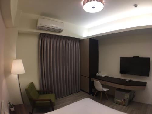 a hotel room with a bed and a desk and a television at 舒悅文旅 台中逢甲店 Sway in Taichung