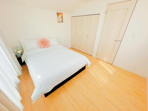 a bedroom with a white bed and a wooden floor at 吉屋 in Tokyo