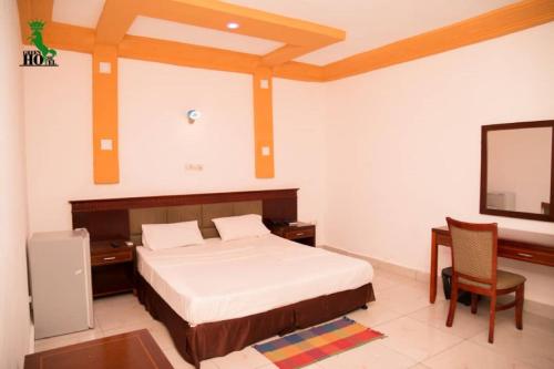 Dormitorio con cama, escritorio y TV en New Green Horse Hotel, en Cotonou