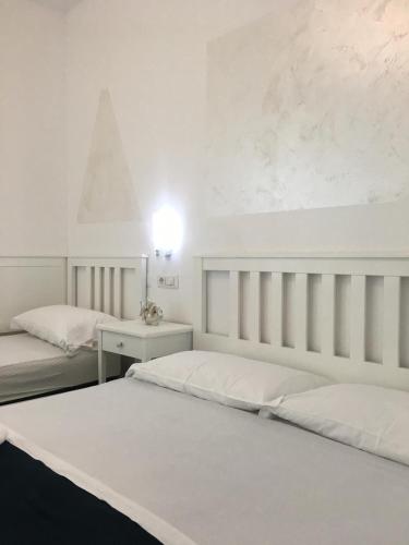 a white bedroom with two beds and a table at B&B A casa di Picci in Santa Domenica