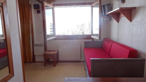a red couch in a room with a window at BORSAT 4 in Tignes