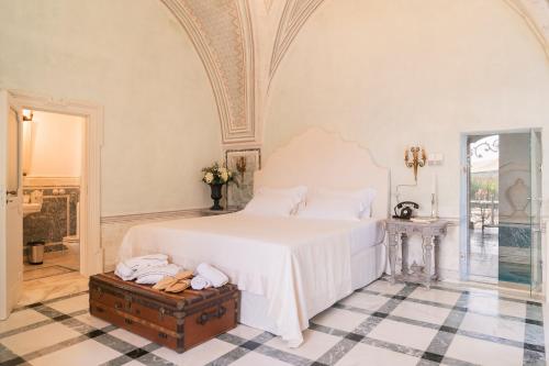 a bedroom with a large white bed with a wooden trunk at Tenuta Mosè Charming House&Relais Gallipoli in Gallipoli