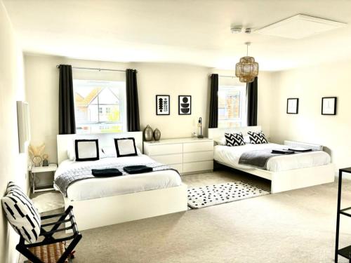 a bedroom with two beds and a chair in it at Stansted Coach House - Apartment Hotel in Elsenham