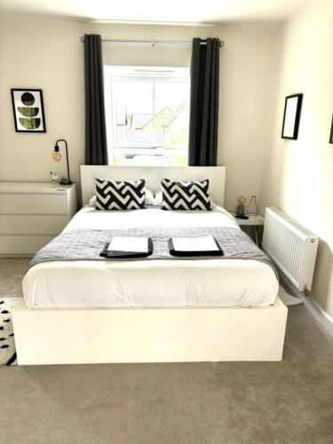 a bedroom with a large white bed with black and white pillows at Stansted Coach House - Apartment Hotel in Elsenham