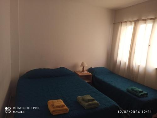 twee bedden in een kamer met twee handdoeken erop bij Hospedaje Los Macaes 2 in Comodoro Rivadavia