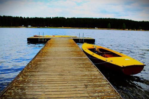 a yellow boat parked next to a dock on a lake at Dom Pracy Twórczej Macondo in Miedzno