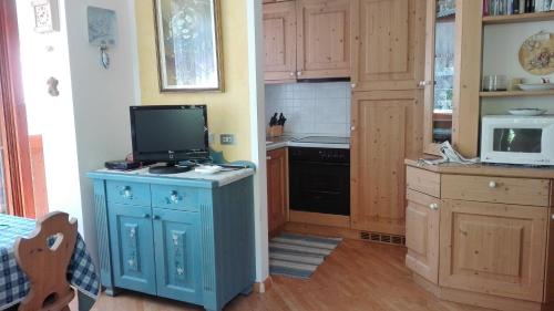 a kitchen with a tv on top of a blue cabinet at Campitello House in Campitello di Fassa