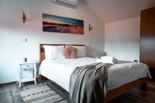a bedroom with a bed with white sheets and a picture on the wall at Refúgio Nariz do Mundo (Casa do Meio) in Cabeceiras de Basto