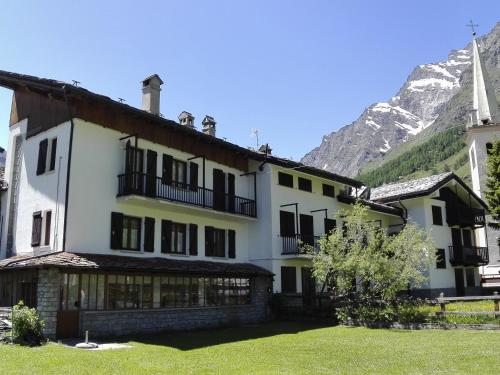 a large white building with a mountain in the background at Case Gran Paradiso Rhemes Notre Dame in Rhêmes-Notre-Dame
