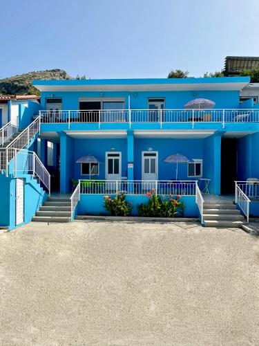 a blue building with stairs and umbrellas at Villa Denny in Borsh