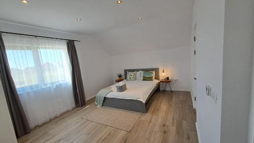 a white bedroom with a bed and a large window at Homestay near motorway in Giarmata