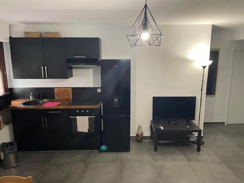 une cuisine avec des armoires noires, un bureau et une lampe dans l'établissement Appartement neuf et moderne face gare St Charles, à Marseille
