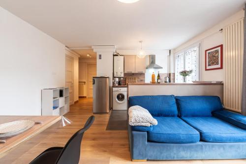 a living room with a blue couch and a kitchen at ANNECY Centre - Charmant T2 in Annecy