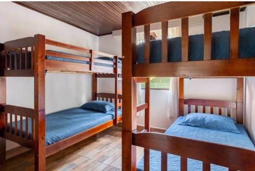 two bunk beds in a room with two blue beds at Pousada Demuner's House - Espaço Aconchegante Itaipava in Petrópolis