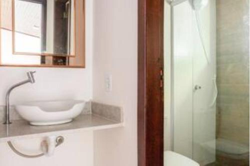 a bathroom with a sink and a glass shower at Pousada Demuner's House - Espaço Aconchegante Itaipava in Petrópolis