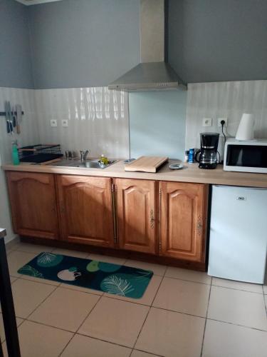 a kitchen with wooden cabinets and a microwave at IL'Ô VOLCAN in Sainte-Rose