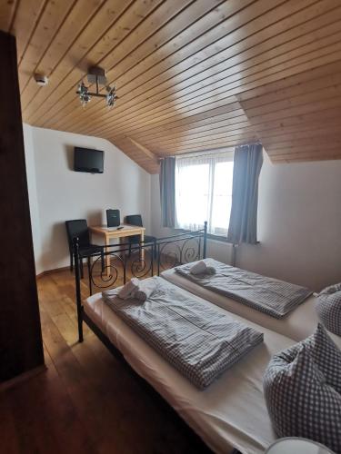two beds in a room with a wooden ceiling at Hotel Karwendelblick in Urfeld