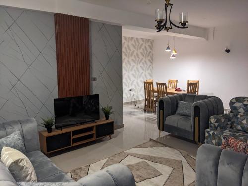 a living room with couches and a flat screen tv at Casa Feliz - Stylish 2 Bedroom Apartment in Addis Ababa