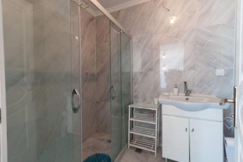 La salle de bains est pourvue d'un lavabo et d'une douche en verre. dans l'établissement 4 Yatak Odalı Şık Villa, à Milas