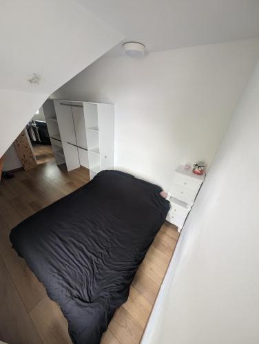 - une chambre blanche avec un lit noir dans l'établissement Appartement cosy- centre de Douvres la Delivrande, à Douvres-la-Délivrande