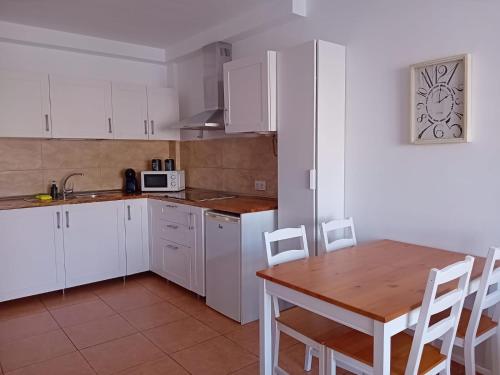 - une cuisine avec des placards blancs, une table et des chaises dans l'établissement Apartamento Stefi, à Arrecife
