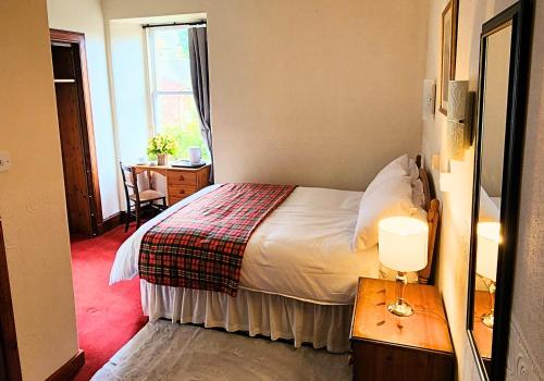 a bedroom with a bed and a table with a lamp at The Retreat Hotel in Strathpeffer