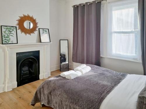 een slaapkamer met een bed, een open haard en een spiegel bij 2 bedroom-2 mins walk to Station in Kent