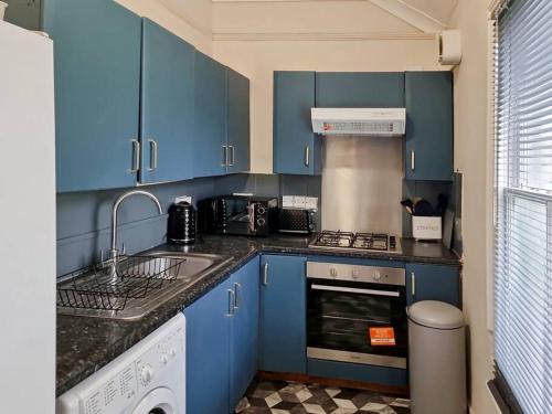 2 bedroom-2 mins walk to Station في Kent: مطبخ ازرق مع مغسلة وغسالة صحون