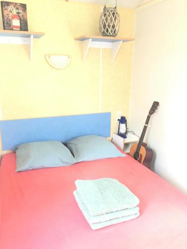een slaapkamer met een rood bed met een gitaar bij Gîte pura vida in Périssac