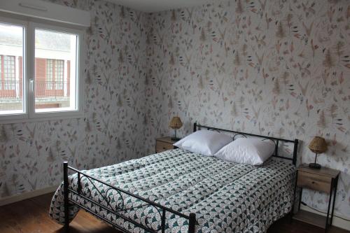 une chambre avec un lit avec un papier peint fleuri dans l'établissement Maison 2 chambres, de centre ville, avec cour exposition sud, à 300 m du port, à Saint-Vaast-la-Hougue