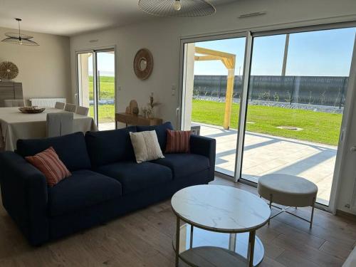 un salon avec un canapé bleu et une table dans l'établissement Gîte des couleurs avec SPA, à Chicheboville