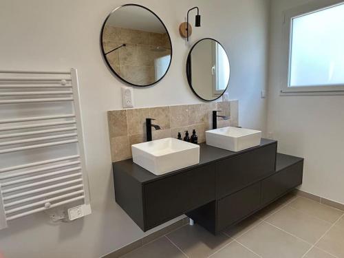 ein Badezimmer mit zwei Waschbecken und einem großen Spiegel in der Unterkunft Gîte des couleurs avec SPA in Chicheboville