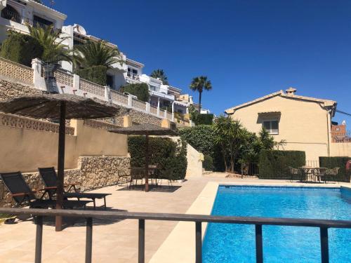 a swimming pool with chairs and an umbrella next to a building at Casa Bella Vista in Moraira