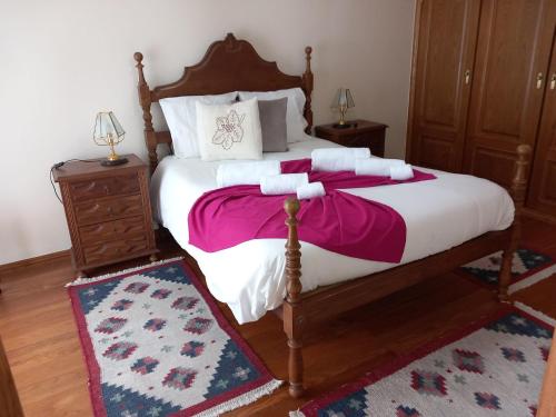 a bedroom with a large bed with pink and white sheets at Casa de S Bento in Rio Caldo