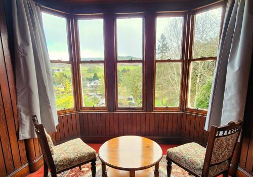 a room with a table and two chairs and windows at The Retreat Hotel in Strathpeffer
