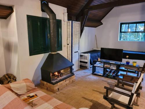 a living room with a fireplace and a tv at Chalé do Lopo in Extrema