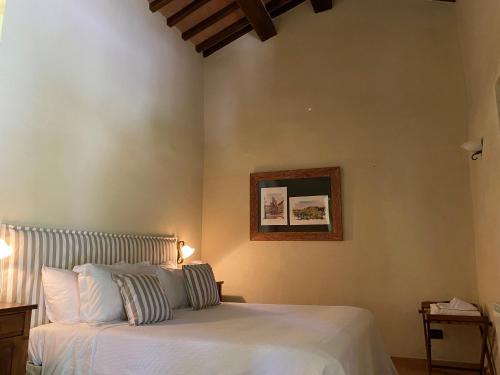 NottolaにあるVilla Montebellaの白いベッドと壁の絵が備わるベッドルーム1室が備わります。