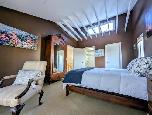 Oceanfront Crackling Cove Cottage NEW في Prospect Harbor: غرفة نوم بسرير كبير وكرسي