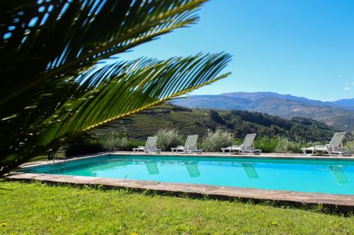 una piscina con sillas y montañas en el fondo en Quinta de Baixo en Vila Marim