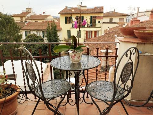 uma mesa e cadeiras de pátio com um vaso de plantas numa varanda em FLORENCE ROOFTOP RETREAT em Florença